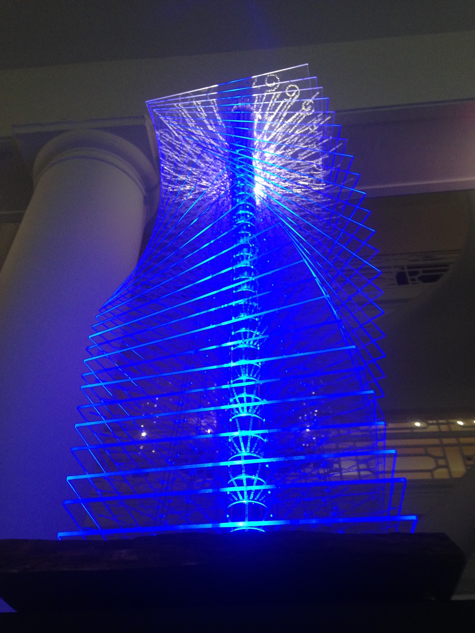 art exhibit piece with overlapping acrylic panels lit up by a blue LED light.