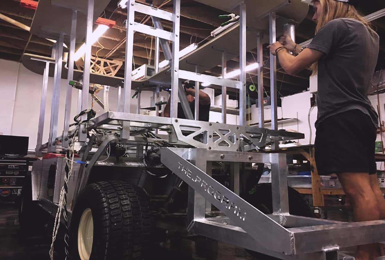 custom fabricated golf cart with metal frame and two men making adjustments.