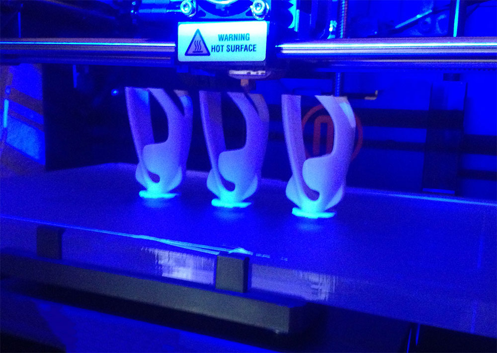 maker bot 3d printer printing white pieces.