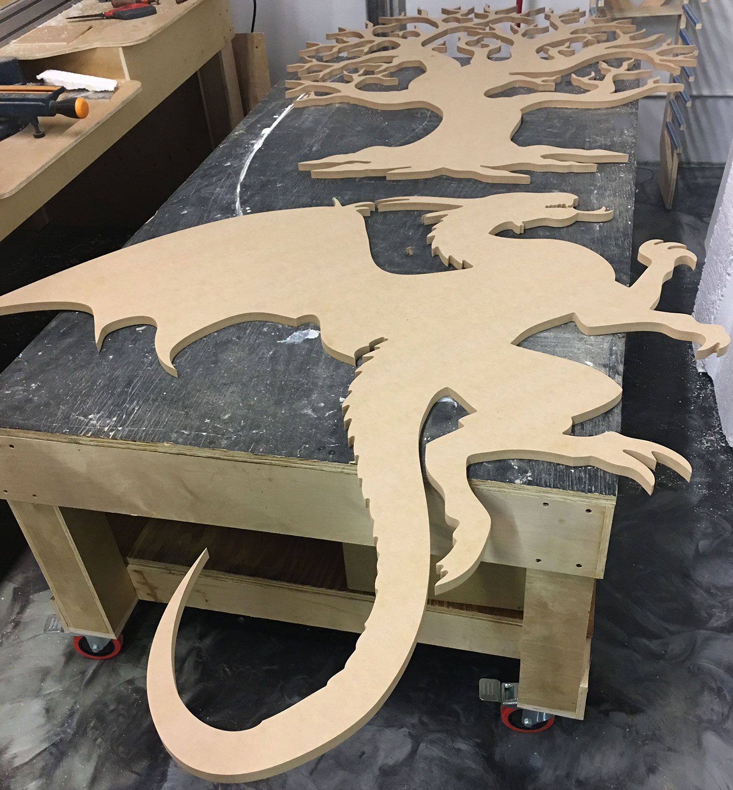 cnc cut figure of a dragon and a tree made out of wood.