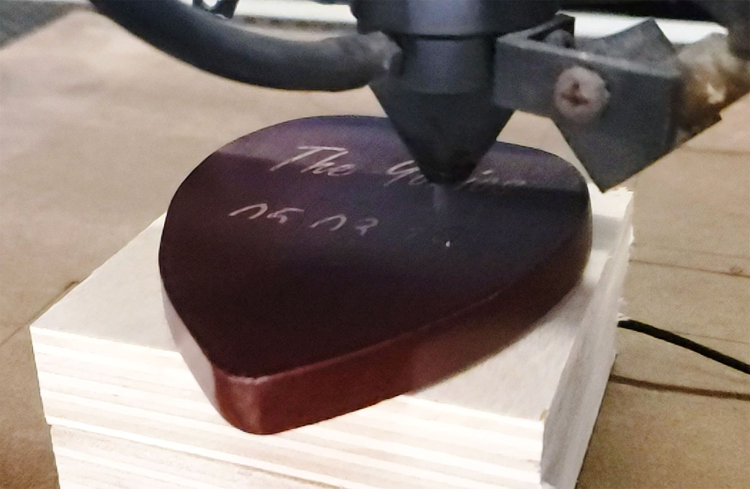 laser machine inscribing words into wooden heart.