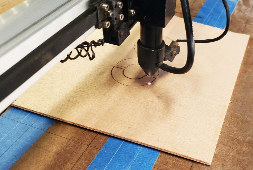 laser machine cutting half circles into wood.