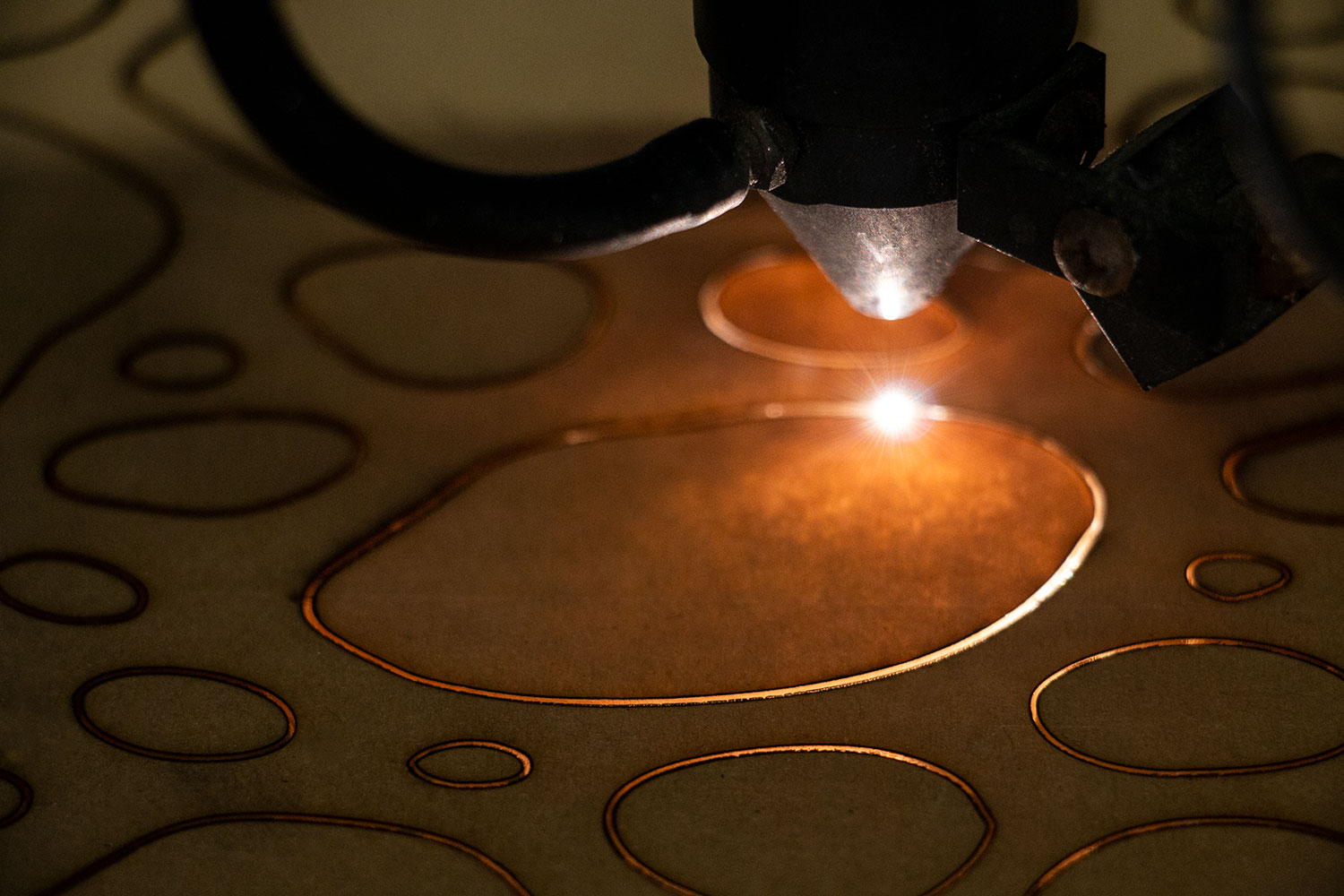 laser machine cutting irregular circles into wood.