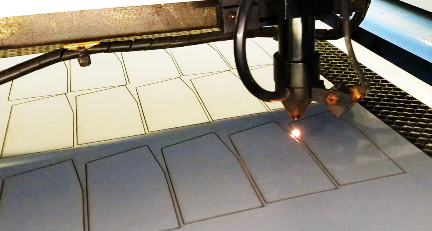laser machine cutting out several small rectangular mirrors.