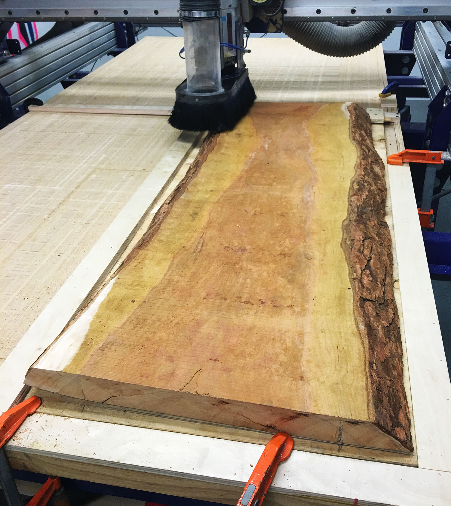 3 axis machine cutting down a piece of live edge wood.