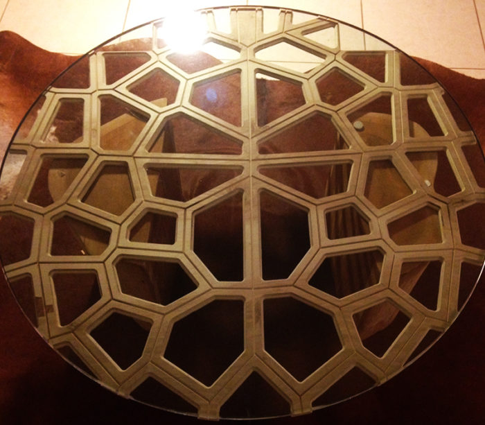honeycomb shaped wooden table top with clear glass sitting atop