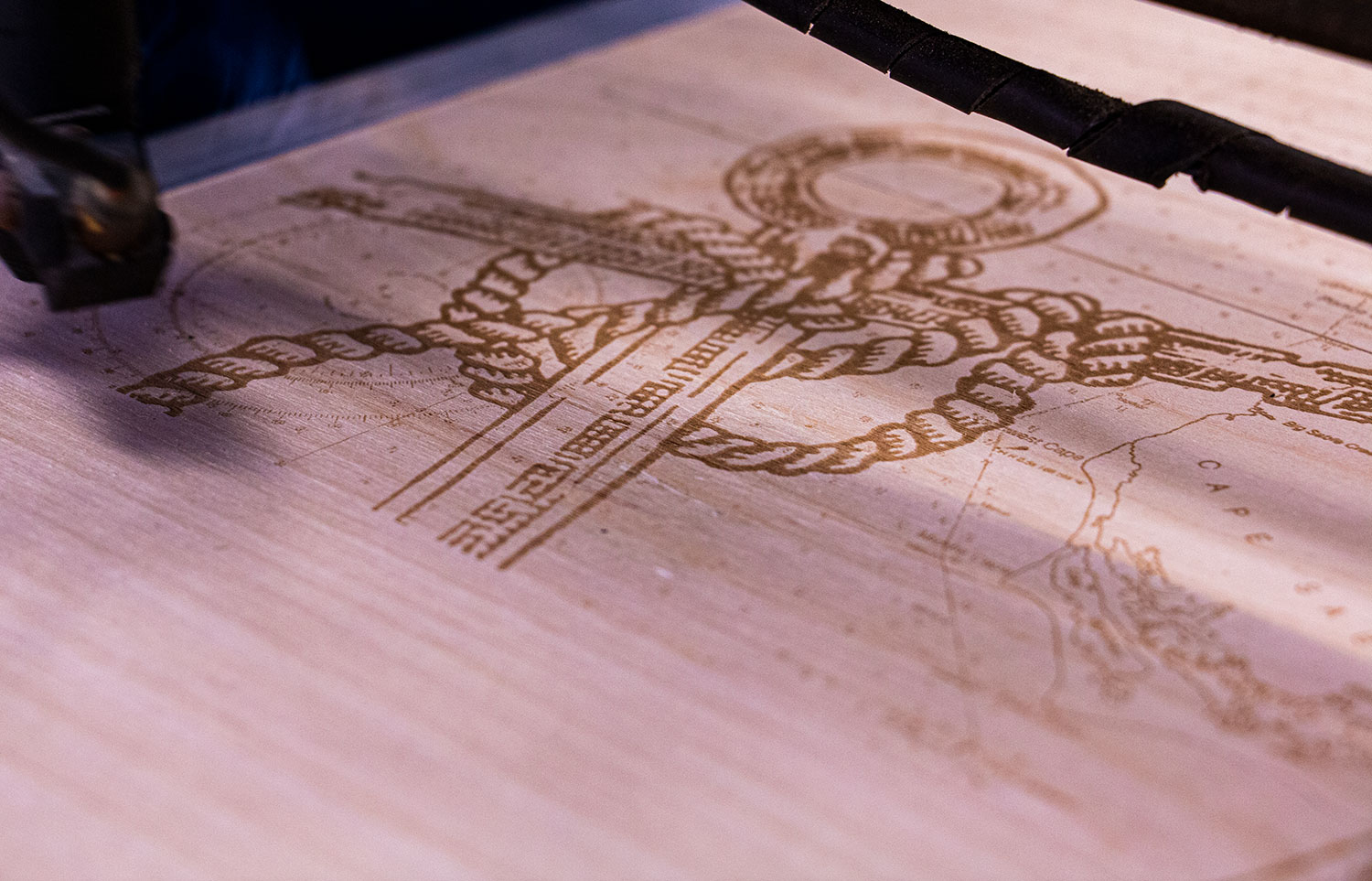 laser maching engraving an anchor and map onto wood